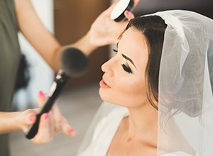 Smiling bride being madeup