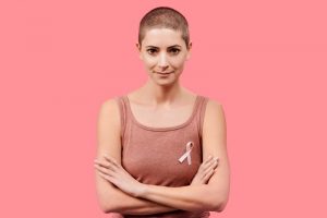 a woman standing with her arms crossed wearing a breast cancer ribbon